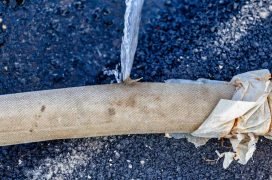 Burst pipe repair with pipe wrapping on asphalt surface.