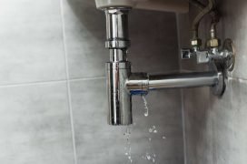 Water leak from a chrome plumbing fixture in a residential kitchen or bathroom.