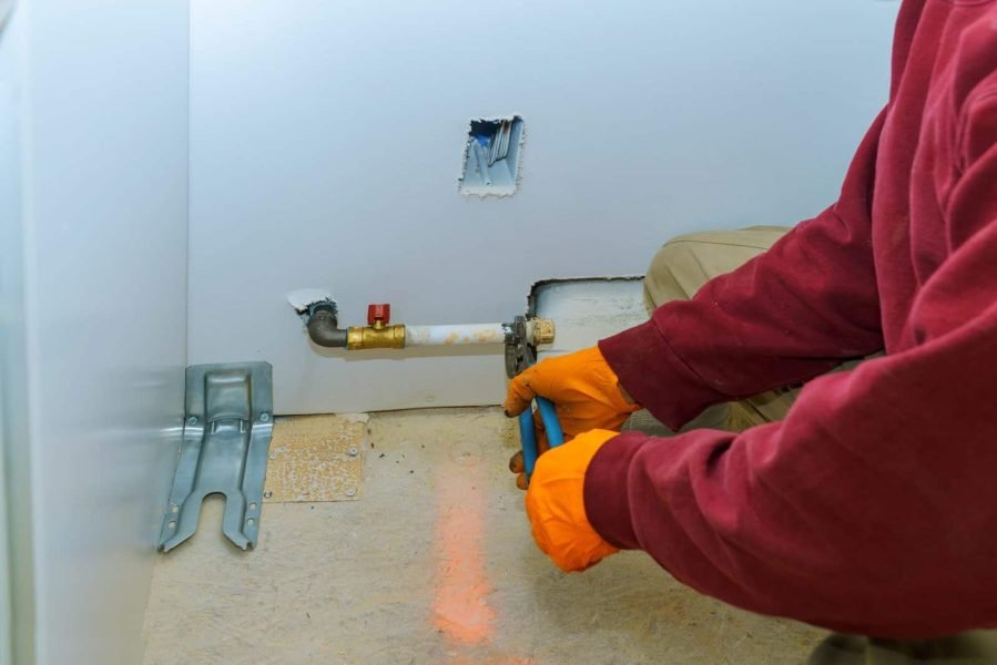 Professional plumber repairing water pipe connection in a residential setting.